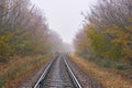 Railroad in fog turns right in autumn forest Royalty Free Stock Photo