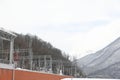 Railroad in the mountains. View of the snow-capped mountains covered with bare trees and firs. Krasnaya Polyana. March