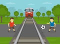 Railroad safety rules and tips. Do not play on or near railway tracks . Male little kids are playing football at level crossing.