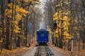 Railroad single track through the woods in autumn. Fall landscape. red stop semaphore signal. Last railway carriage of blue train Royalty Free Stock Photo