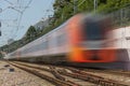 Railroad suburban passenger train passing by in motion at sunset. Railway station with motion blur effect against colorful blue Royalty Free Stock Photo