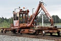 A railroad track tie crane travels on a main line