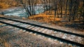 Railroad tracks in autumn forest with frozen river Royalty Free Stock Photo