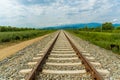 Railroad tracks leading to endless infinity. Meadow landscape and distant mountains. Royalty Free Stock Photo