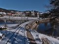 Railroad tracks on the shore of frozen Schluchsee lake with railway bridge and village on sunny winter day. Royalty Free Stock Photo