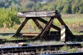 Railroad tracks stop barrier buffer at end of tracks in train station with cracked wooden beam and rusted metal parts overgrown