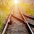 Railroad tracks, with a switch in the foreground, leading to infinity with the red light of the rising sun in the center of the Royalty Free Stock Photo