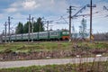 Railroad Train passing by a wooden rural house in a web of wires Royalty Free Stock Photo