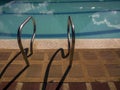 The rails of a swimming pool ladder project their shadow