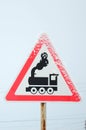 Railway crossing without barrier. A road sign depicting an old black locomotive, located in a red triangle Royalty Free Stock Photo