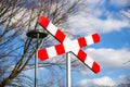 Railway crossing sign against bare trees and cloudy blue sky Royalty Free Stock Photo