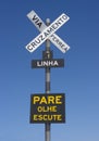 Railway crossing sign written in portuguese in Brazil in front of a blue sky background Royalty Free Stock Photo