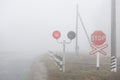 A railway crossing with a working semaphore and a stop sign. In the fog Royalty Free Stock Photo