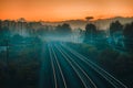 Railway in foggy summer evening with buildings and trees on the background