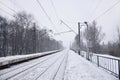 Railway landscape in the cold winter season. Snow-covered railway station platform and foggy overcast sky during a heavy snowfal