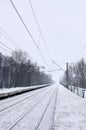 Railway landscape in the cold winter season. Snow-covered railway station platform and foggy overcast sky during a heavy snowfal