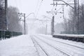 Railway landscape in the cold winter season. Snow-covered railway station platform and foggy overcast sky during a heavy snowfal