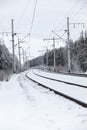 Railway line and rails on winter cold cloudy day, electric poles with wires Royalty Free Stock Photo