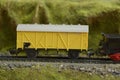 Railway model with yellow freight train car and landscape details