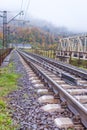 Railway in the mountains. Railroad tracks in autumn mountains. Railroad in foggy morning landscape. Transportation industry Royalty Free Stock Photo