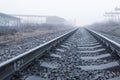 The railway rails go away in the foggy morning
