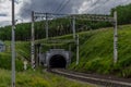 Railway, road path with a tunnel in the green mountains hills with trees, wire pillars, clouds