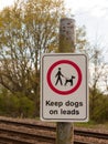 A Railway Safety Sign Saying Keep Dogs on Leads in White and Red