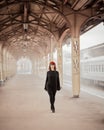 Railway station. Beautiful woman goes from train looking at camera. Female travels light. Middle-aged lady Royalty Free Stock Photo