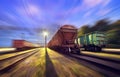 Railway station with cargo wagons in motion at night. Royalty Free Stock Photo