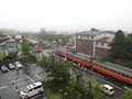 Railway station, red train, car park, building and streets at the Japanese countryside Royalty Free Stock Photo