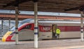 Railway station with a waiting train and crew loading a package Royalty Free Stock Photo