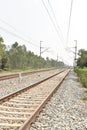 Railway track with the background of sky, and green trees on both sides of the track Royalty Free Stock Photo