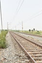 Railway track with the background of sky, and green trees on both sides of the track