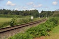 Railway track with meadows, trees and blue sky