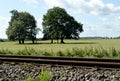 Railway track with meadows, trees and blue sky