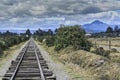 Railway track surrounded by greenery under a beautiful cloudy sky Royalty Free Stock Photo