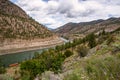 Railrod Tracks Running on Both Sides of a River in the Mountains and Cloudy Sky