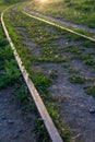 Railway tracks up to sunset. Old rusty rails and wooden sleepers. The sun rays and glare of the sun. Uncut grass grows