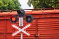 Railway traffic light against the background of a red freight car. Red prohibition light is on. The concept of an