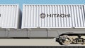 Railway transportation of containers with Hitachi logo. Editorial 3D rendering