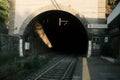 Railway tunnel in Italy with sunlight falling on it and signs on the right in Italian and English