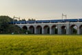 Railway viaduct with passing trains and cars in an underpass during a sunny day with moving clouds in the sky Royalty Free Stock Photo