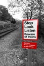 Railway warning sign in black and white with red signpost reading `Stop Look Listen Beware of trains` Royalty Free Stock Photo