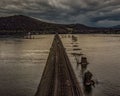Railways spans the lake water with view of the mountains in the background on a cloudy day Royalty Free Stock Photo