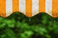 Rain. Awning on a balcony and drops of water on a natural colorful background during a spring day. Royalty Free Stock Photo