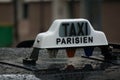 Rain on a black Paris taxi with a white Taxi Parisien sign on top