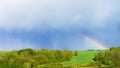 Rain and a bright rainbow in the blue sky at the same time. The concept of weather forecast and climate change. Rainbow during the Royalty Free Stock Photo