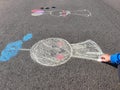 Rain chasing doll kid drawing with colourful pastel sidewalk chalks on the pavement