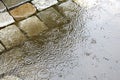 Rain in the city - puddles on the cobblestone street pavement -