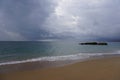 Rain clouds over the ocean. Atlantic. Wet sand of the beach. Surf waves and black rocks Royalty Free Stock Photo